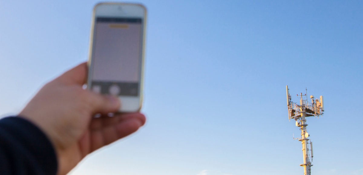 Person holding cell phone up to 5G Tower