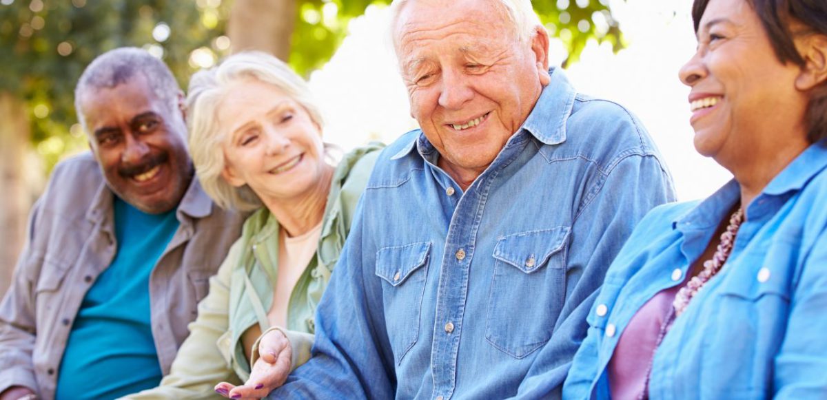 Four seniors smiling and chatting outside