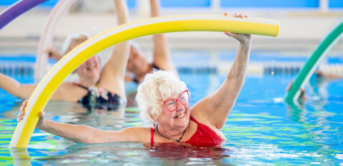 Senior using pool noodle for water aerobics.