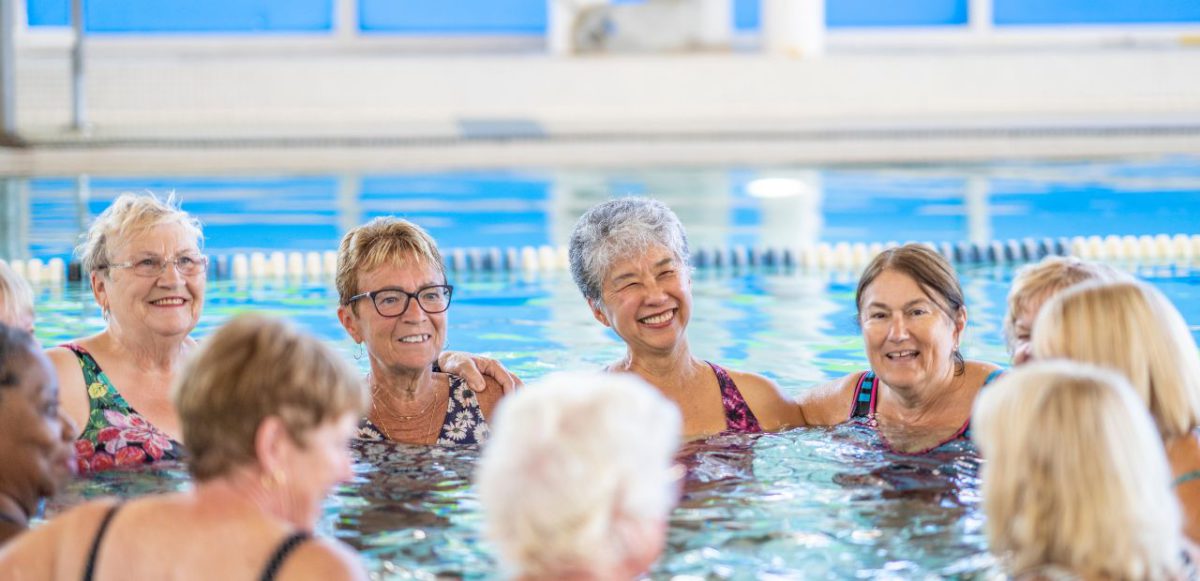 Group of seniors gathered in circle in pool