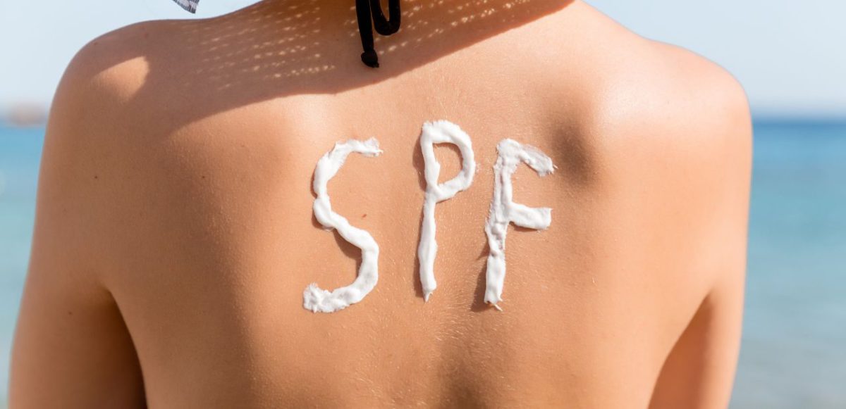 Sunscreen used to write "SPF" on a beachgoing woman's upper back.