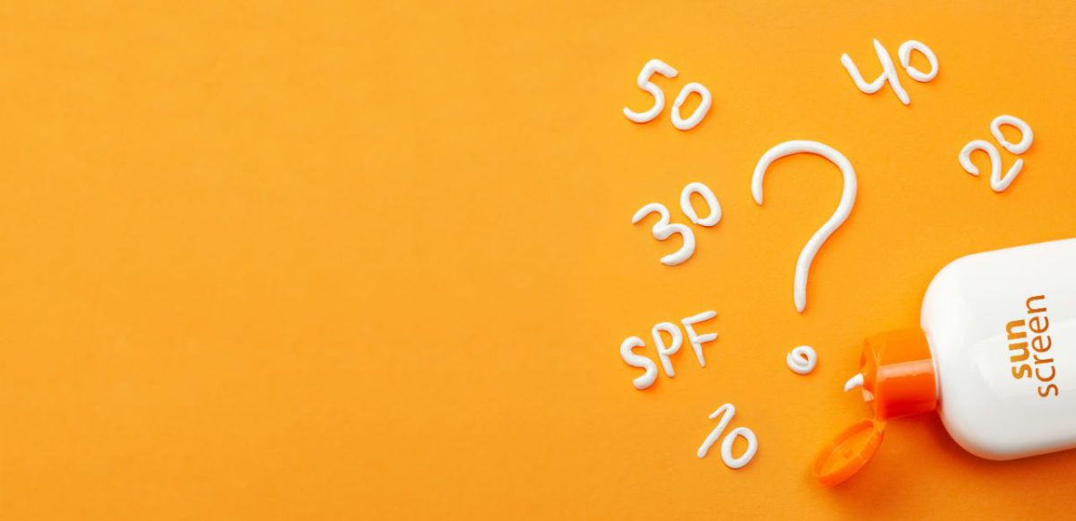The letters 'SPF', the numbers 10, 20, 30, 40, and 50, and a large question mark written with sunscreen. The bottle of sunscreen lies open in the lower corner.