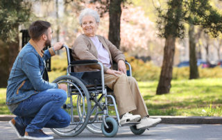 elderly parent in wheelchair visited by adult son outside