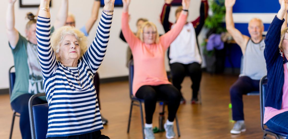 A group of seniors performing chair exercises.