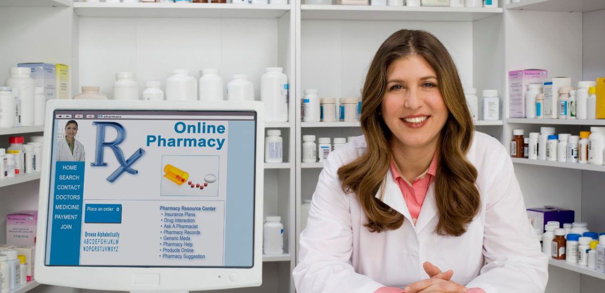 A pharmacist sitting next to a screen displaying an online pharmacy